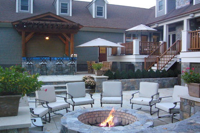 Ejemplo de patio clásico renovado grande en patio trasero con brasero y adoquines de piedra natural