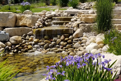 Idées déco pour un grand jardin à la française arrière classique au printemps avec une cascade, une exposition ensoleillée et des galets de rivière.