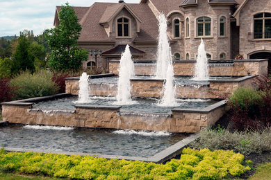 Idee per un giardino formale chic esposto in pieno sole davanti casa in estate con fontane e pavimentazioni in pietra naturale
