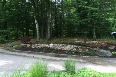 Inspiration for a mid-sized rustic partial sun front yard stone retaining wall landscape in Portland Maine for summer.