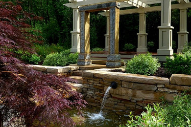 Foto de jardín clásico grande en patio trasero con fuente, exposición total al sol y adoquines de piedra natural