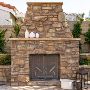 Geräumiger Mediterraner Garten hinter dem Haus mit Kamin, direkter Sonneneinstrahlung und Natursteinplatten in Los Angeles