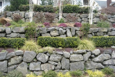 На фото: летний регулярный сад среднего размера на переднем дворе в классическом стиле с подпорной стенкой, полуденной тенью и покрытием из каменной брусчатки