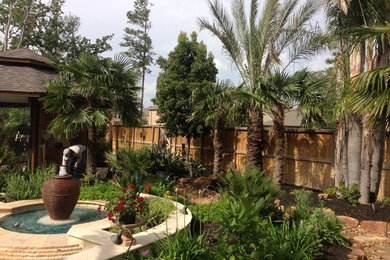 Modelo de jardín exótico grande en verano en patio trasero con jardín francés, exposición total al sol y adoquines de piedra natural