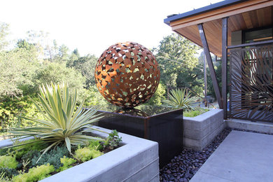 Imagen de jardín de secano moderno de tamaño medio en otoño en patio delantero con fuente, exposición parcial al sol y adoquines de hormigón