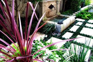Foto de jardín clásico de tamaño medio en patio lateral con jardín francés, fuente, exposición parcial al sol y adoquines de hormigón
