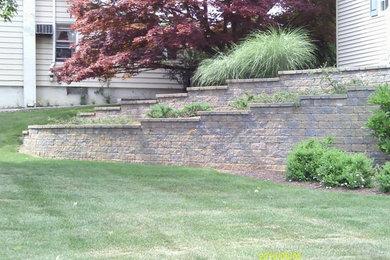 Photo of a mid-sized traditional partial sun front yard brick retaining wall landscape in New York.