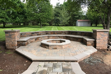 This is an example of a large traditional partial sun backyard concrete paver formal garden in Philadelphia with a fire pit.