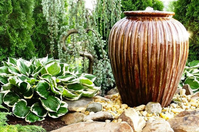 Imagen de jardín de tamaño medio en patio trasero con fuente, exposición total al sol y adoquines de piedra natural
