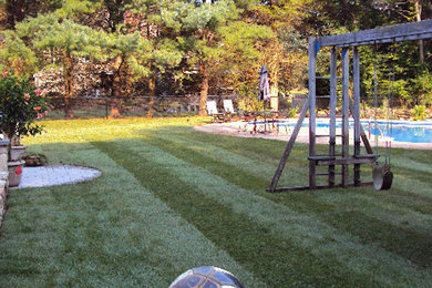 Ejemplo de jardín clásico grande en patio trasero con parque infantil y exposición parcial al sol
