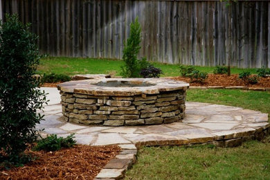 Photo of a large classic back partial sun garden in Little Rock with a fire feature and natural stone paving.