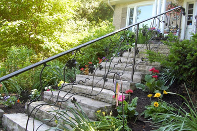 Diseño de jardín clásico grande en primavera en patio delantero con jardín francés, exposición total al sol y adoquines de piedra natural