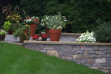 Aménagement d'un jardin de taille moyenne avec un mur de soutènement, une exposition partiellement ombragée, une pente, une colline ou un talus et des pavés en pierre naturelle.