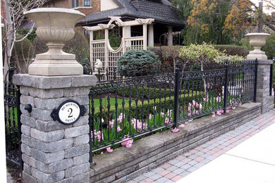 This is an example of a mid-sized traditional full sun front yard stone landscaping in Toronto for spring.