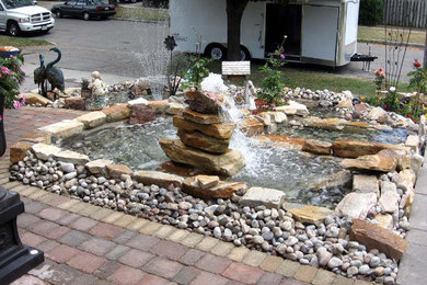 Design ideas for a mid-sized contemporary full sun front yard stone pond in Toronto for summer.