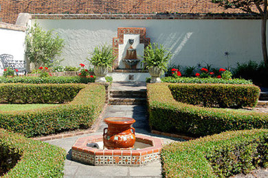 Foto de jardín tradicional de tamaño medio en verano en patio trasero con jardín francés, fuente, exposición total al sol y adoquines de hormigón