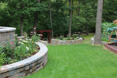Design ideas for a large traditional full sun backyard concrete paver retaining wall landscape in New York for summer.
