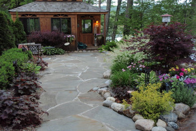 Imagen de jardín de estilo americano grande en verano en patio trasero con exposición parcial al sol y adoquines de piedra natural