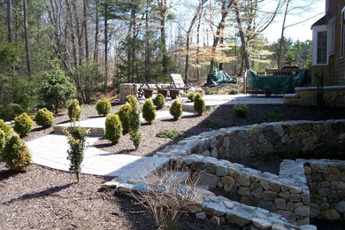 Imagen de jardín clásico renovado grande en patio trasero con muro de contención, exposición parcial al sol y adoquines de piedra natural
