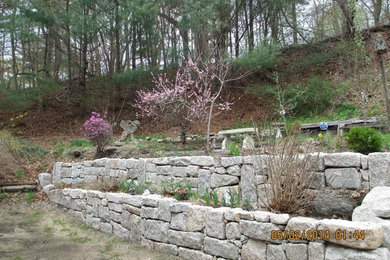 Ejemplo de jardín clásico grande en patio trasero con muro de contención y gravilla