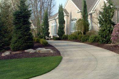 This is an example of a large traditional shade front yard concrete paver driveway in Cleveland.