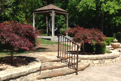 Photo of a mid-sized traditional partial sun backyard stone landscaping in Other.