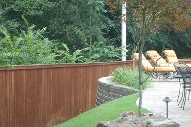 Idée de décoration pour un jardin arrière tradition de taille moyenne avec un mur de soutènement et des pavés en pierre naturelle.