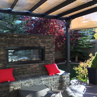 Kleiner Moderner Garten hinter dem Haus mit Kamin, direkter Sonneneinstrahlung und Dielen in Calgary