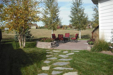 Exempel på en mellanstor klassisk bakgård i delvis sol, med en stödmur och naturstensplattor