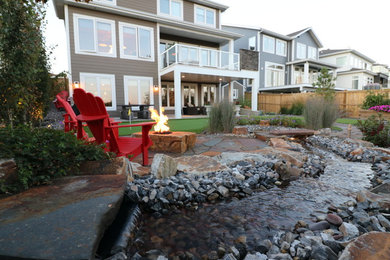 This is an example of a small rustic full sun backyard stone landscaping in Edmonton with a fire pit for summer.