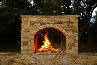 Photo of a mid-sized rustic backyard stone landscaping in Dallas with a fireplace.