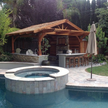 Outdoor kitchen with custom wood roof, granite countertops, and paver patio