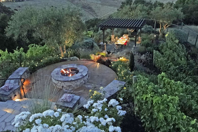 This is an example of a mid-sized traditional full sun backyard brick landscaping in San Francisco with a fire pit for spring.
