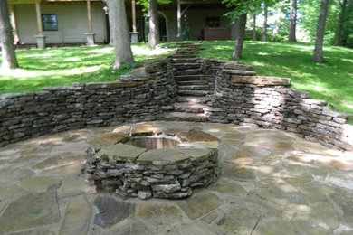 Photo of a mid-sized rustic full sun backyard stone landscaping in Chicago with a fire pit.