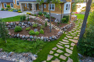 Design ideas for a huge full sun side yard stone retaining wall landscape in Minneapolis for summer.