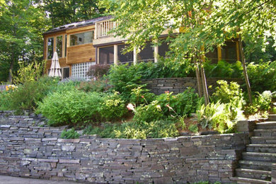 Modelo de jardín clásico de tamaño medio en patio delantero con muro de contención, exposición parcial al sol y adoquines de hormigón