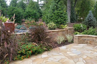 Diseño de jardín tradicional de tamaño medio en patio trasero con muro de contención y adoquines de piedra natural