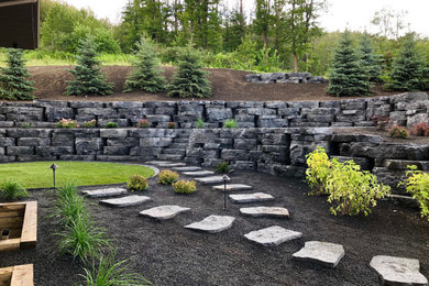 Inspiration for a large backyard brick retaining wall landscape in Calgary.