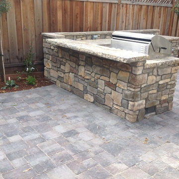 Paver patio accompanied by a barbecue with stone veneer and a granite countertop