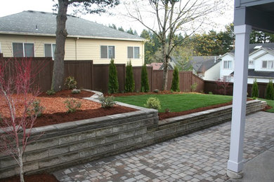 Foto de jardín clásico grande en patio trasero con muro de contención y adoquines de hormigón