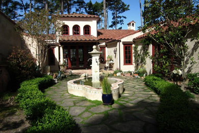 Foto de jardín mediterráneo de tamaño medio en verano en patio delantero con fuente, exposición parcial al sol, adoquines de piedra natural y jardín francés