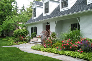 На фото: участок и сад на переднем дворе в классическом стиле с покрытием из каменной брусчатки и клумбами с