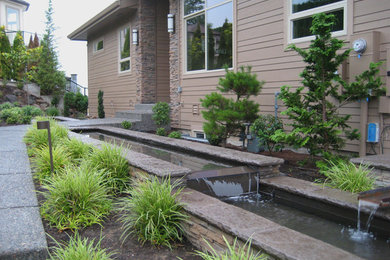 Modelo de jardín de estilo zen de tamaño medio en patio delantero con fuente y adoquines de hormigón