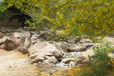 This is an example of a mid-sized southwestern drought-tolerant and partial sun backyard water fountain landscape in Los Angeles for summer.