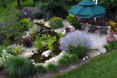 Ejemplo de jardín bohemio de tamaño medio en primavera en patio trasero con estanque, exposición total al sol y adoquines de piedra natural