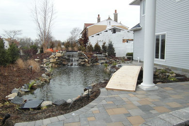 Photo of a mid-sized coastal partial sun backyard concrete paver water fountain landscape in New York for summer.