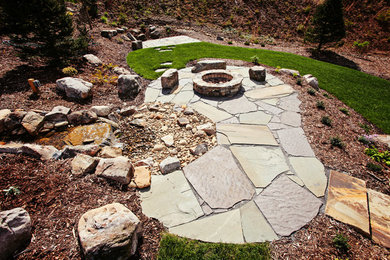 Design ideas for a mid-sized traditional full sun backyard stone landscaping in Charlotte with a fire pit.