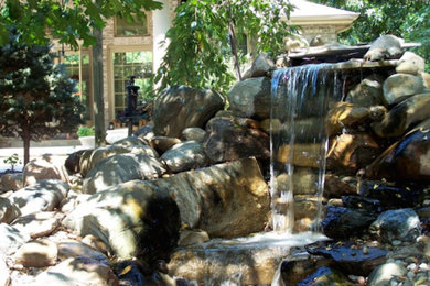 Ejemplo de jardín clásico en patio trasero con fuente y adoquines de piedra natural