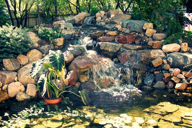 Diseño de jardín rústico de tamaño medio en verano en patio trasero con estanque, exposición parcial al sol y adoquines de piedra natural