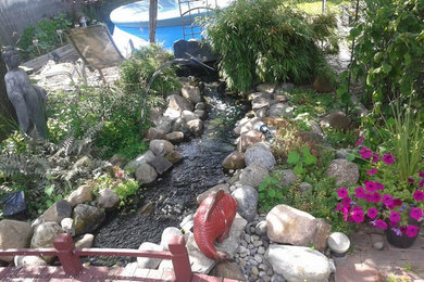 Foto de jardín de tamaño medio en patio trasero con fuente y adoquines de piedra natural